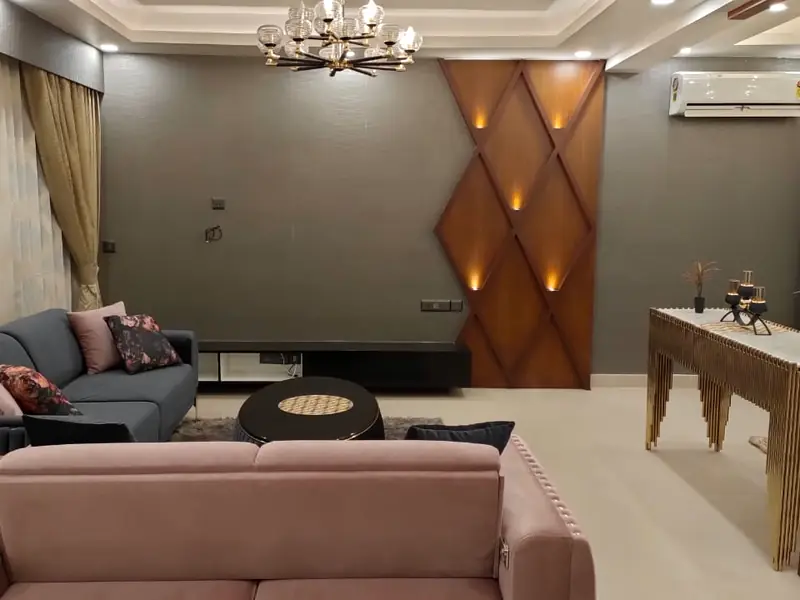 Finished living room with a wood panel feature wall, chandelier and cove lighting