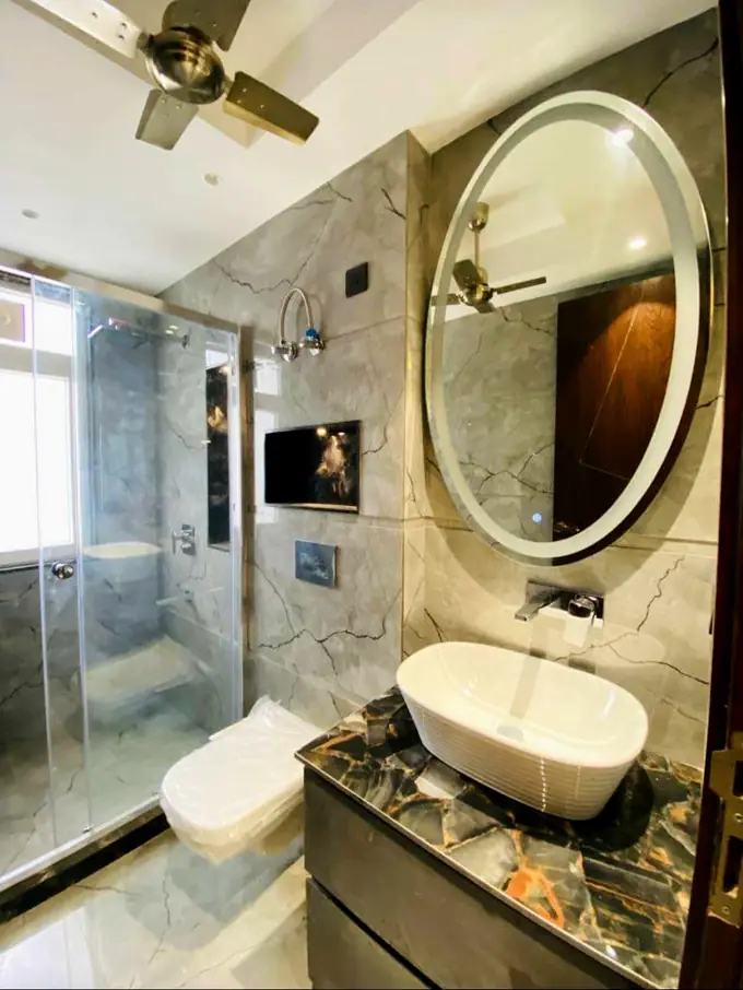 Bathroom with marble cladding, a lit oval mirror and a counter-top basin