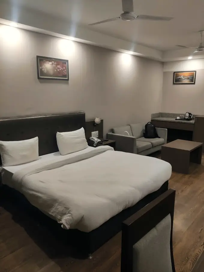 Bedroom with an upholstered headboard, wooden floor and a seating corner