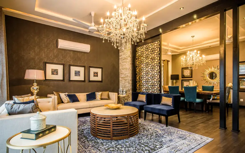 Living room opening into a dining room, with chandeliers and a jali partition