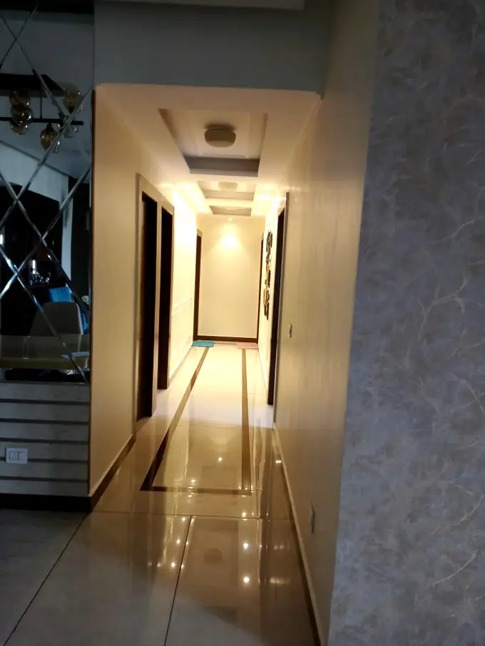 Passage with mirror panelling and a lit ceiling channel