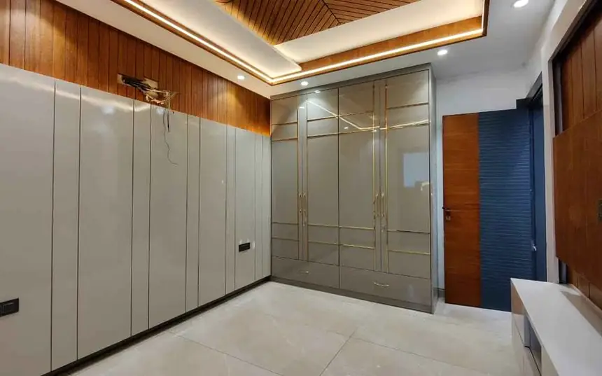 Fitted wardrobes in ivory shutters running the length of a bedroom wall