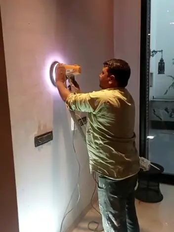 Worker drilling a point into a plastered wall
